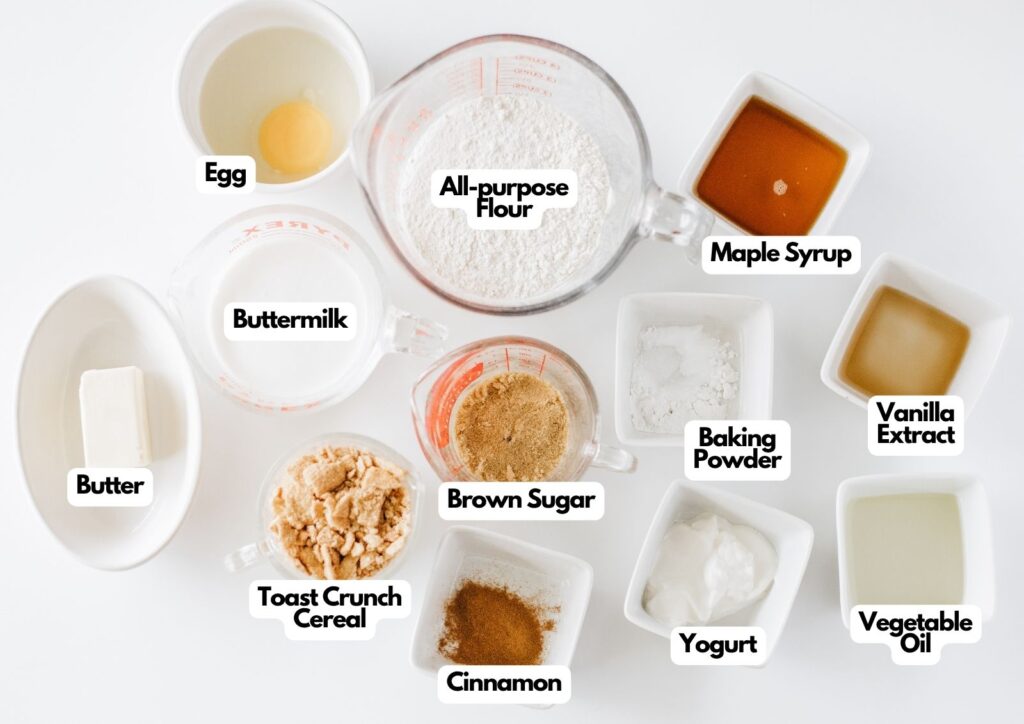 Various baking ingredients in bowls and measuring cups are labeled, including flour, maple syrup, egg, buttermilk, butter, brown sugar, cereal, cinnamon, baking powder, yogurt, vanilla, and oil—everything you need to create delicious Glazed Cinnamon Crunch Toast Donuts.