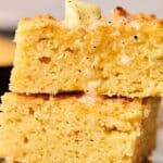 Two pieces of cornbread stacked, topped with a small pat of butter, visibly melting into the deliciously golden cornbread.