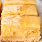 A close-up of three luscious lemon bars showcases a crumbly crust paired with a thick, moist filling.