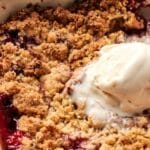 A strawberry dump cake topped with a scoop of melting vanilla ice cream in a dish provides the perfect twist to the classic baked berry crumble.