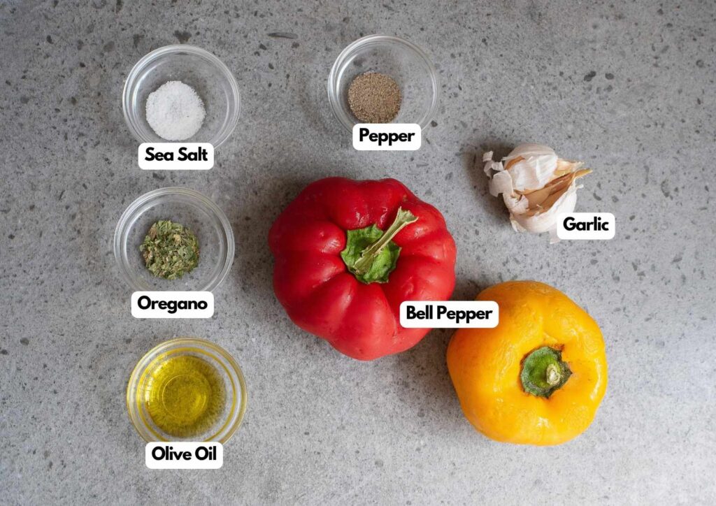 Red and yellow bell peppers, garlic, sea salt, pepper, oregano, and olive oil in labeled bowls on a gray countertop—perfect ingredients for making flavorful grilled peppers.