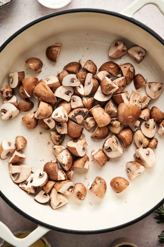 A white pan filled with chopped brown mushrooms, perfect for a hearty mushroom pasta.