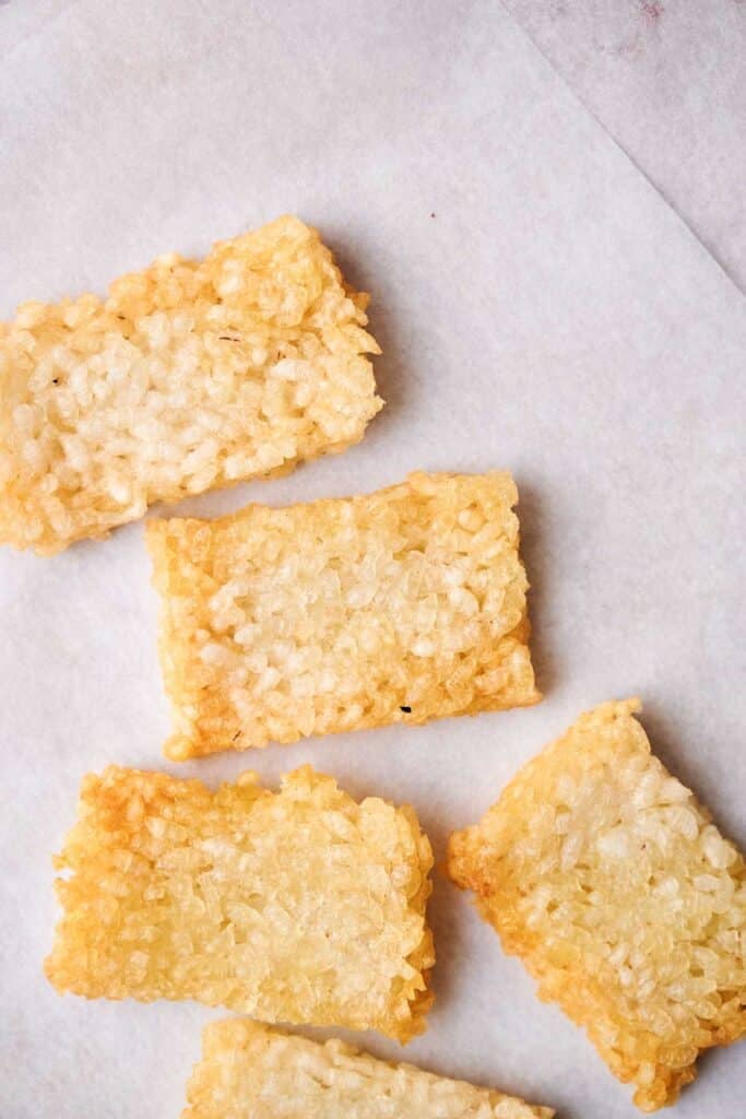 Five crispy rice cakes sit neatly on a sheet of parchment paper.