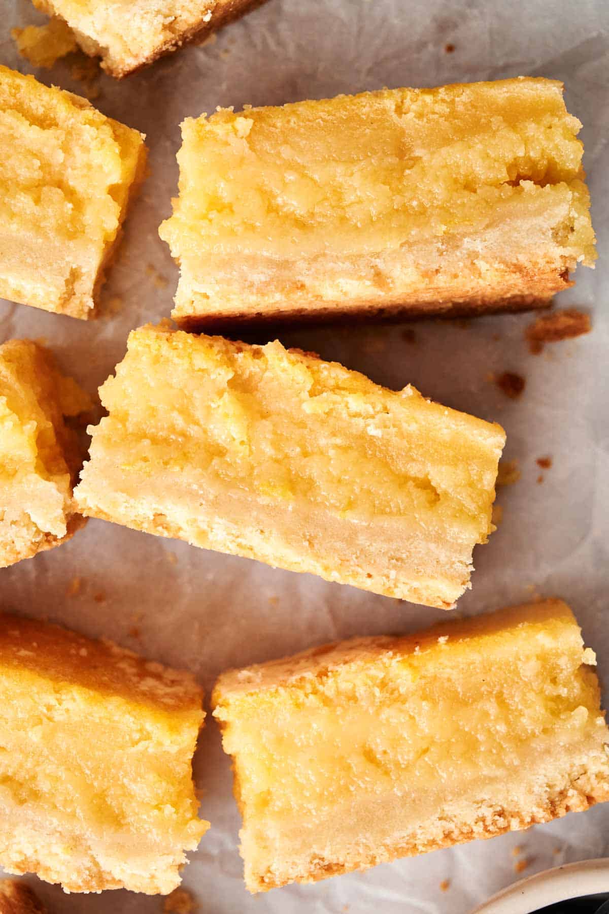 Close-up of several air fryer lemon bars on a light surface. The bars boast a crumbly crust and a bright yellow, smooth lemon filling.