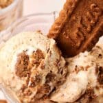 Two scoops of Biscoff Ice Cream with visible cookie chunks are served in a glass bowl, garnished with a whole Lotus Biscoff biscuit.