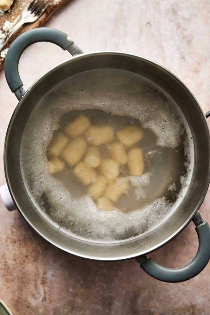 A pot filled with boiling water and potato chunks simmers on the stove, ready for transformation into homemade gnocchi.