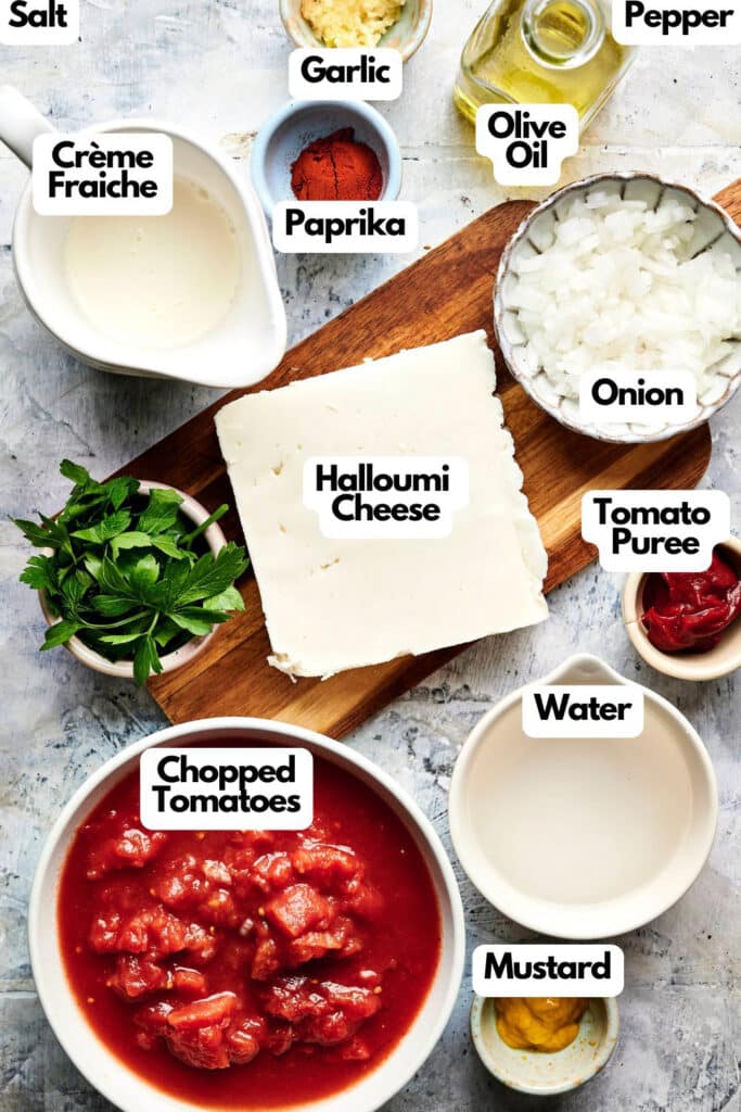 A vibrant spread features Halloumi Stroganoff essentials: halloumi cheese, chopped tomatoes, onions, garlic, a dash of salt and pepper. Olive oil and tomato puree mingle with water, mustard, and paprika while crème fraîche adds richness. Fresh parsley offers the finishing touch.