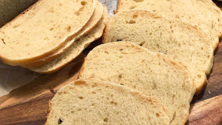 Six slices of white bread arranged on a wooden cutting board.