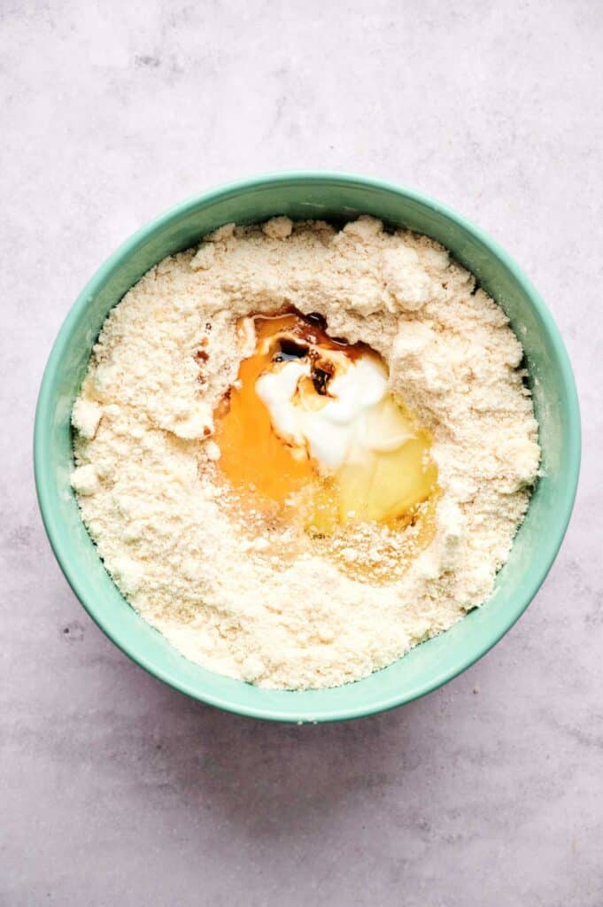 A mixing bowl with flour, yogurt, eggs, and vanilla extract before being mixed together for delicious homemade scones.