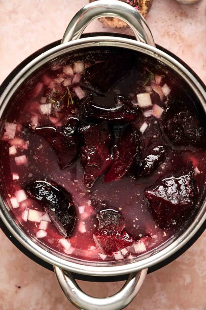 A pot filled with chopped beets, diced onions, and liquid, likely being prepared for a delicious air fryer beet soup.