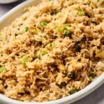 A white oval dish filled with Egg Fried Rice, garnished with chopped green onions.