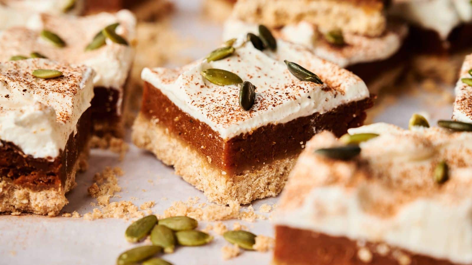 A close-up of a sliced pumpkin loaf cake with white icing and pumpkin seeds on top, showing its moist and crumbly texture.