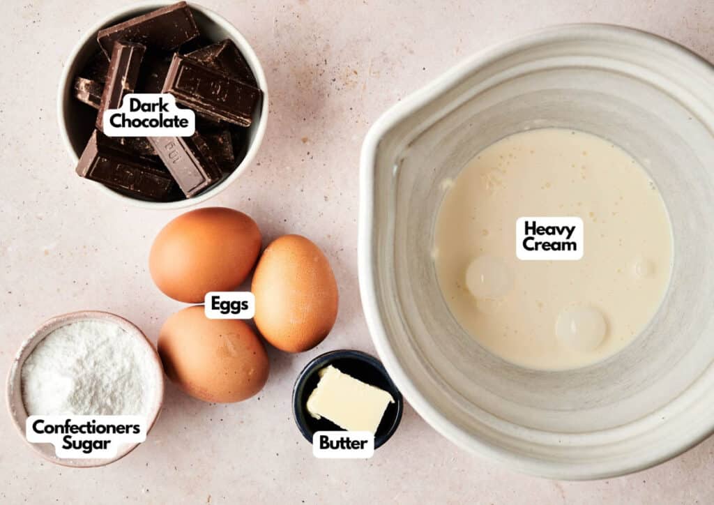 A bowl of heavy cream, three eggs, a bowl of dark chocolate pieces, a dish of confectioners sugar, and a piece of butter are arranged on a countertop&mdash;everything you need to create rich Chocolate Mousse.