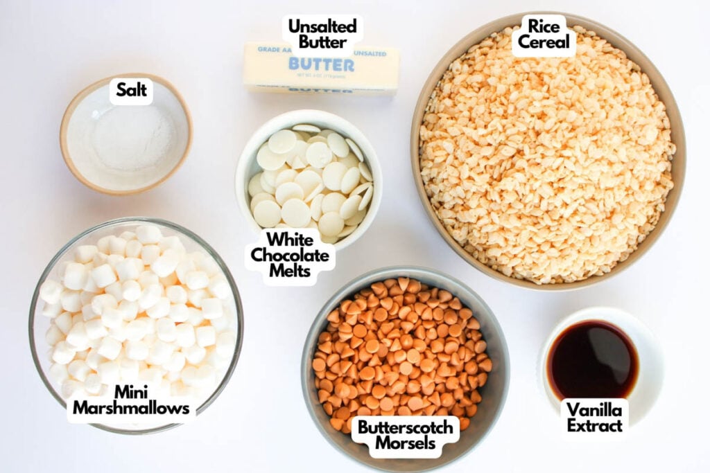 Bowls containing ingredients for Butterscotch Rice Treats&mdash;rice cereal, mini marshmallows, butterscotch morsels, white chocolate melts, salt, vanilla extract, and unsalted butter&mdash;are arranged side by side in a top-down view.