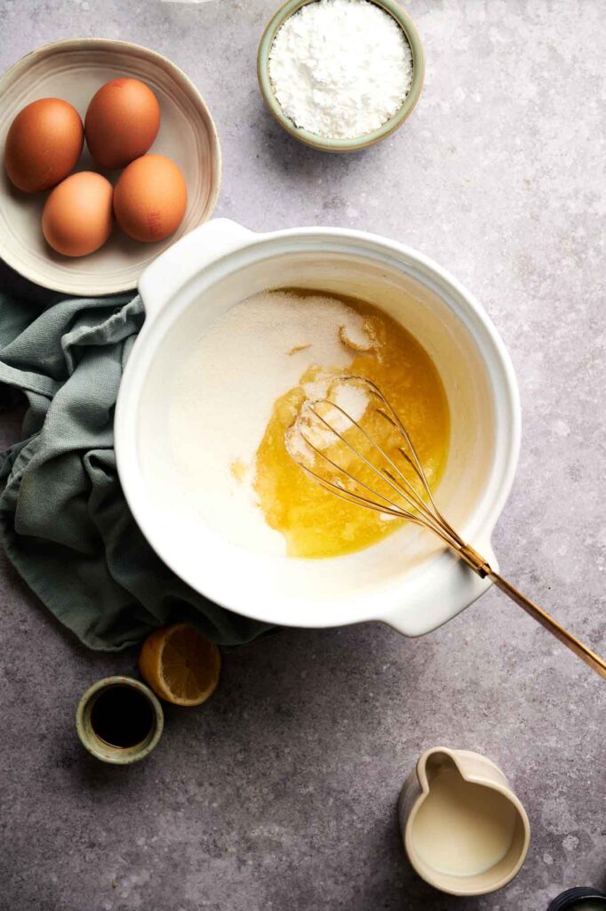 Sugar and melted butter are whisked together in a mixing bowl, the base of the chess pie filling before the eggs are added.