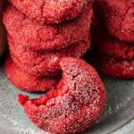 A stack of red Air Fryer Strawberry Cookies, sugar-coated and tempting, with one cookie in front missing a bite, all placed on a gray plate.