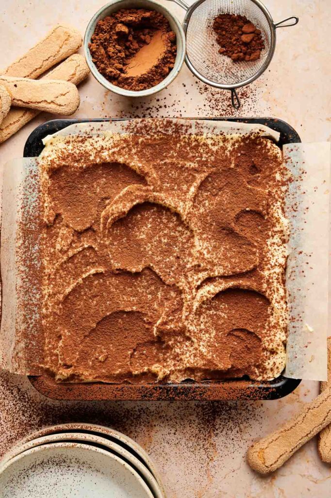 A dusting of cocoa powder covers the top mascarpone layer of tiramisu brownies, dusted with a fine sieve just before serving.