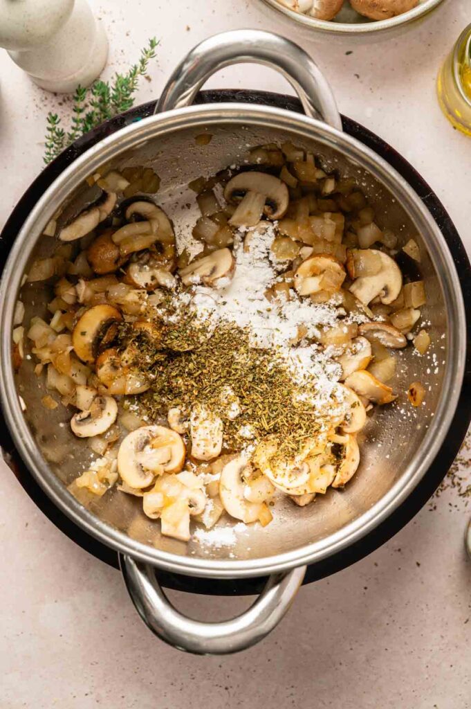 Cornstarch and dried herbs are sprinkled over sautéed mushrooms and onions to form the base of the roux.