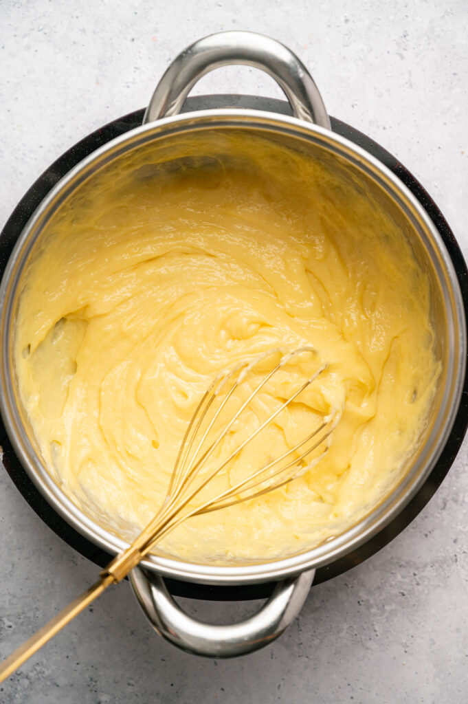 Pastry cream thickens in a saucepan, whisked until smooth and creamy enough to coat the back of a spoon.