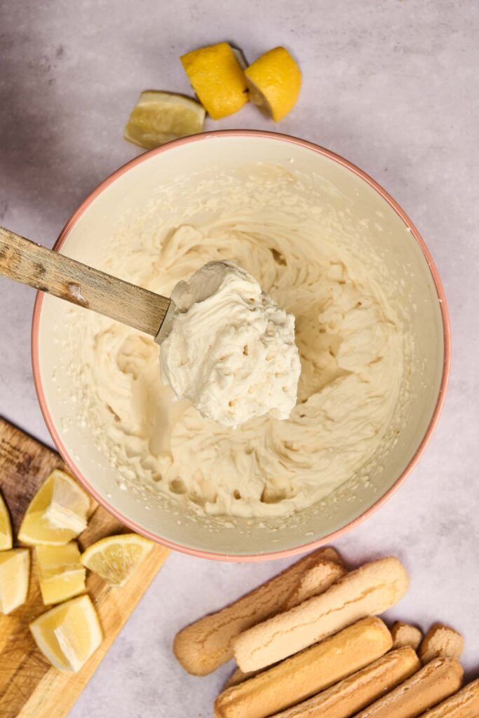 A spatula lifting soft, whipped cream from a bowl, showing its light and airy texture.