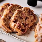 Three slices of Air Fryer Strawberry Bread, topped with a sweet glaze, are neatly arranged on a white rectangular plate.