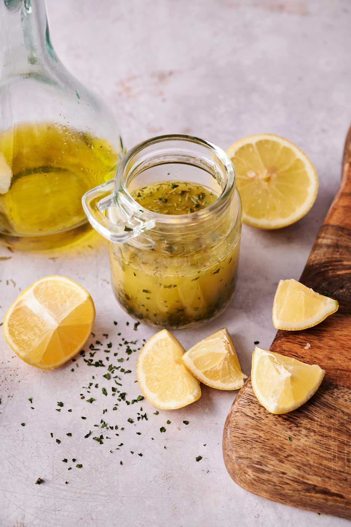 A jar of Lemon Vinaigrette Dressing sits beside fresh lemons, ready to brighten any salad.