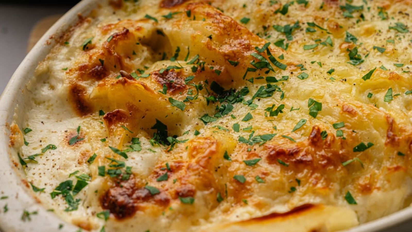 A baked dish with a golden-brown cheese crust, garnished with chopped parsley.