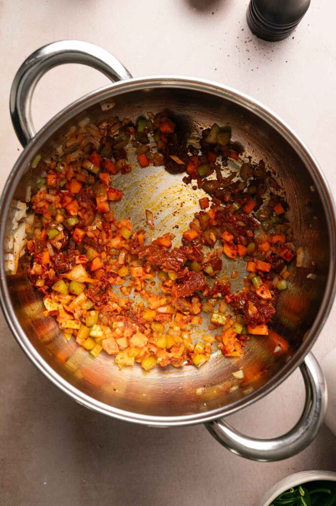 Sun-dried tomatoes, paprika, and tomato paste are stirred into the sautéed vegetables, deepening in color—a delicious base for Marry Me Chickpea Soup.