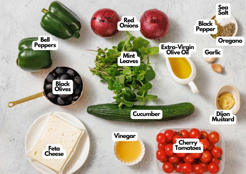 A flat lay of ingredients for a Southern Farmhouse Feta & Veggie Salad, featuring bell peppers, red onions, mint leaves, cucumber, cherry tomatoes, feta cheese, black olives, vinegar, olive oil, garlic, mustard, oregano, black pepper and sea salt.