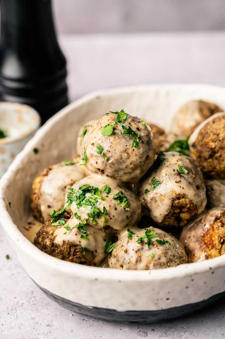 A bowl of vegetarian meatballs topped with savory sauce.