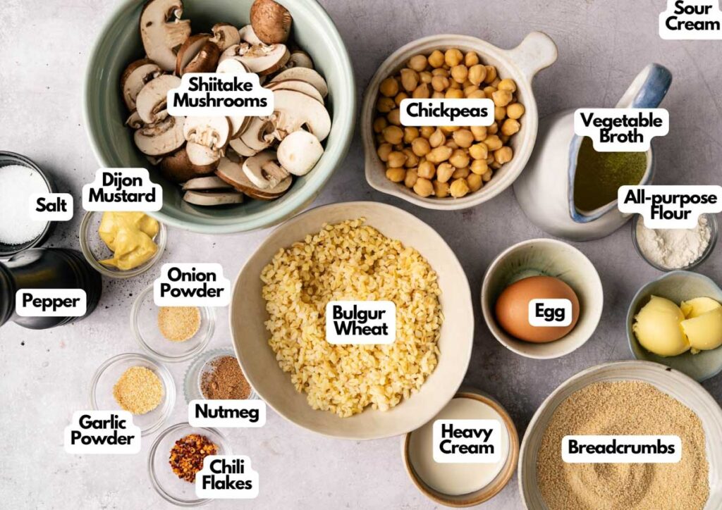 An overhead view of labeled ingredients in bowls and dishes, including shiitake mushrooms, chickpeas, bulgur wheat, egg, sour cream, spices, and more on a light surface—perfect for making delicious Vegetarian Meatballs.