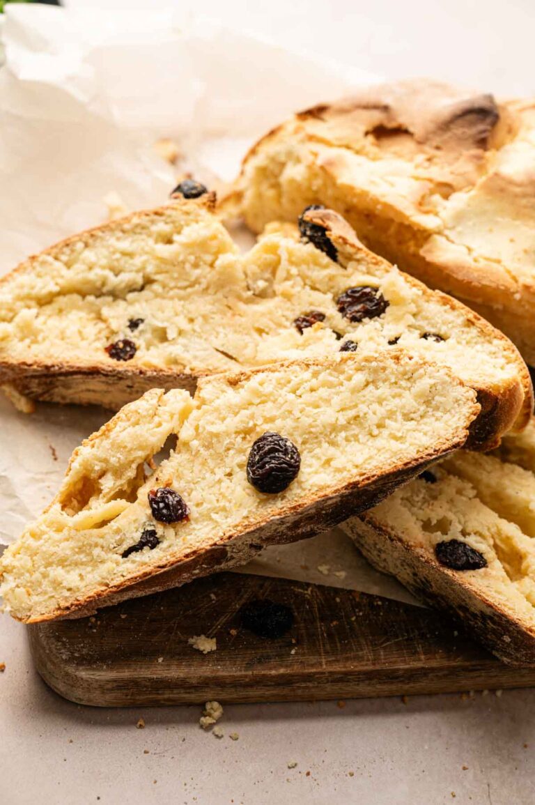 Sliced loaf of Irish Soda Bread with visible raisins, placed on a wooden cutting board with parchment paper in the background.