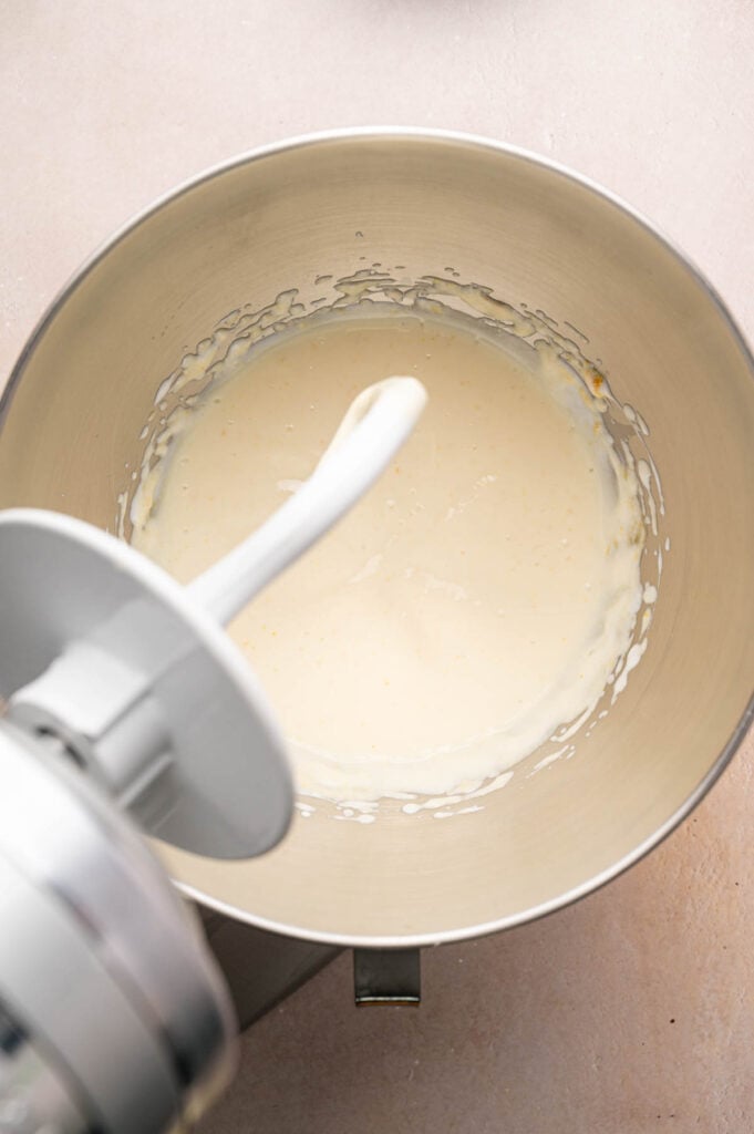 Metal mixing bowl with creamy Irish Soda Bread batter inside, attached to a stand mixer with a paddle attachment, viewed from above.