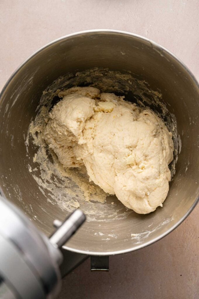 A metal mixing bowl containing a ball of Irish Soda Bread dough, partially mixed and clinging to the sides of the bowl.