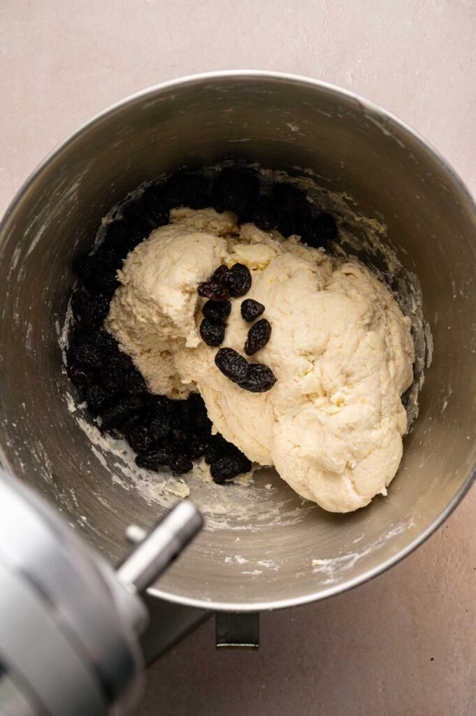 Mixing bowl containing Irish Soda Bread dough and raisins, viewed from above. The bowl is attached to a stand mixer.