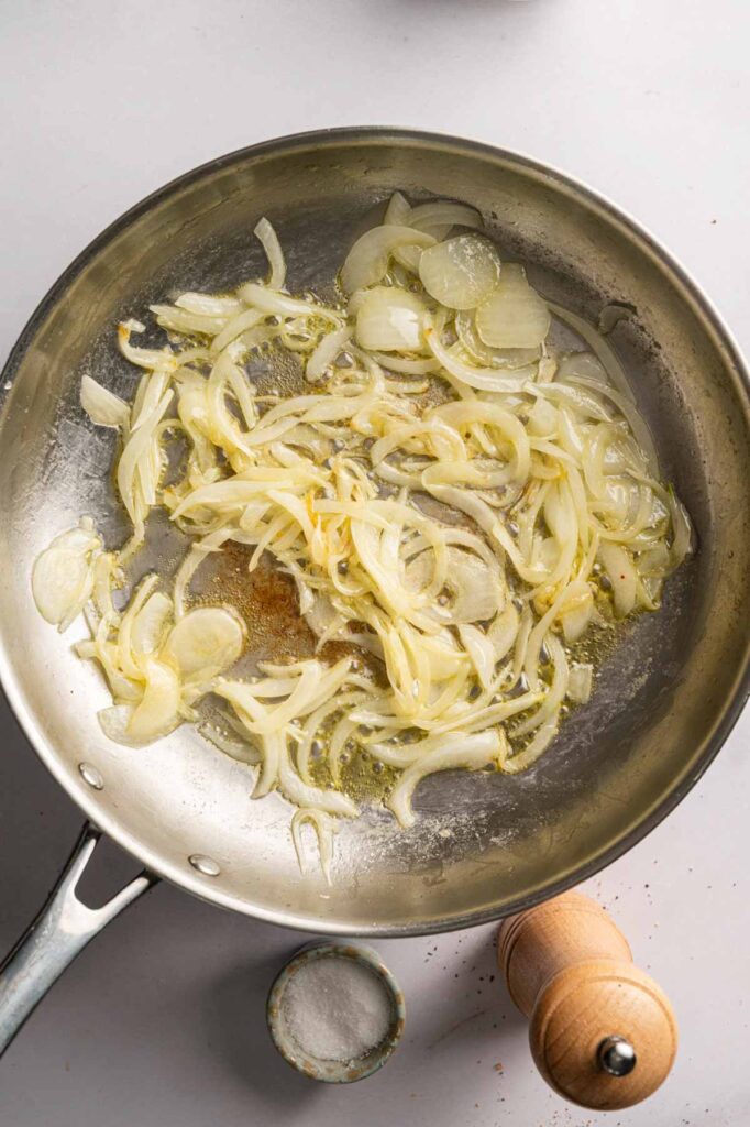 Sliced onions cook down in a skillet with butter and olive oil, turning soft and lightly golden.
