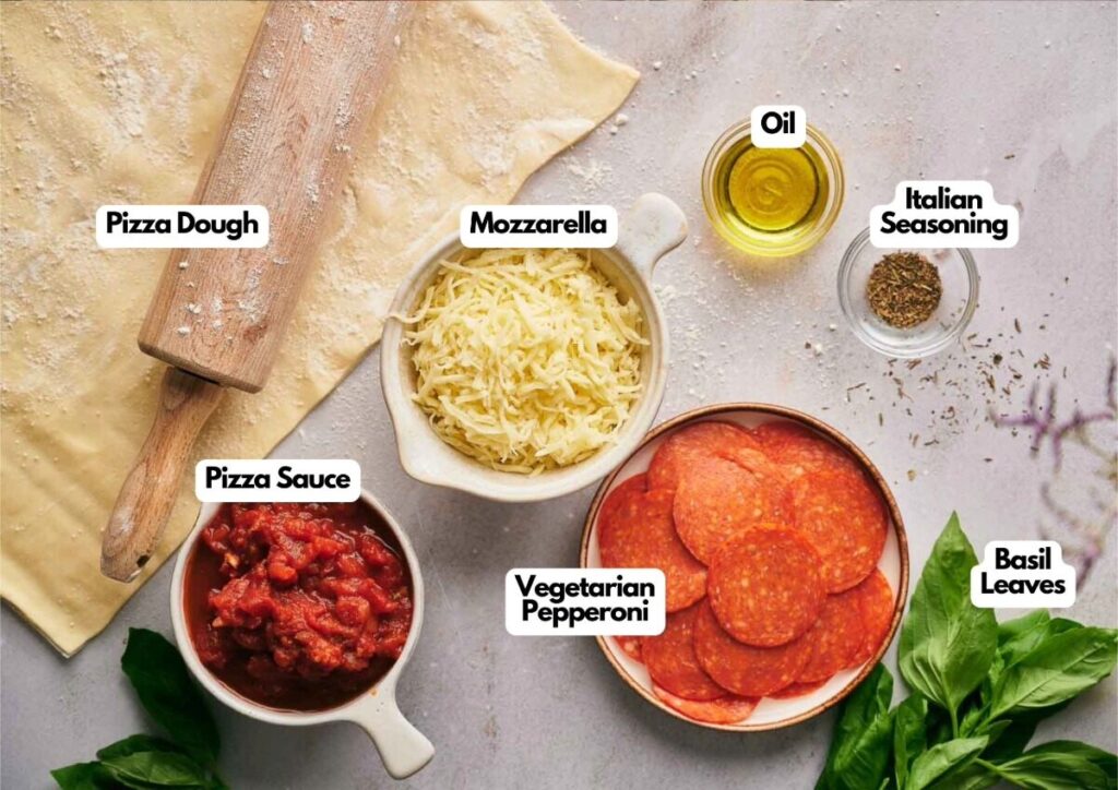 Pizza dough, mozzarella, oil, Italian seasoning, pizza sauce, vegetarian pepperoni, and basil leaves arranged on a surface&mdash;each ingredient labeled for perfect Air Fryer Pizza Rolls.