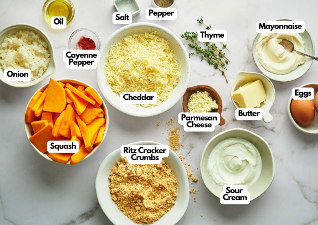 Ingredients for a Yellow Squash Casserole are arranged on a white surface, including squash, onion, oil, cheddar, salt, pepper, cayenne, thyme, mayonnaise, eggs, butter, Parmesan, Ritz crumbs, and sour cream.