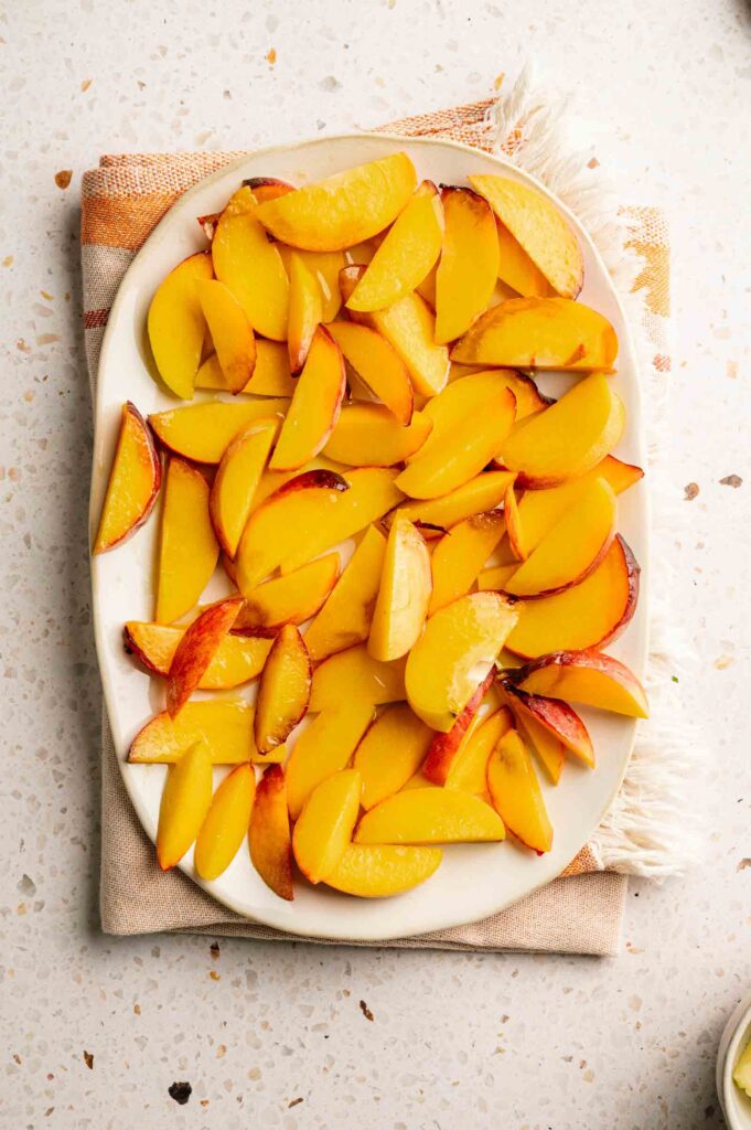 Halved peaches are brushed with olive oil, ready to be grilled until charred and caramelized.